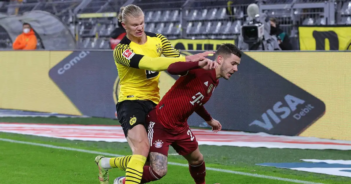 Borussia Dortmund's Erling Haaland shoves Bayern Munich's Lucas Hernandez to the floor.